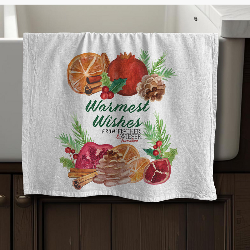 Decorative towel with festive design featuring pomegranates, oranges, and cinnamon sticks on a kitchen towel rack.