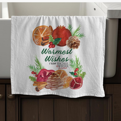 Decorative towel with festive design featuring pomegranates, oranges, and cinnamon sticks on a kitchen towel rack.