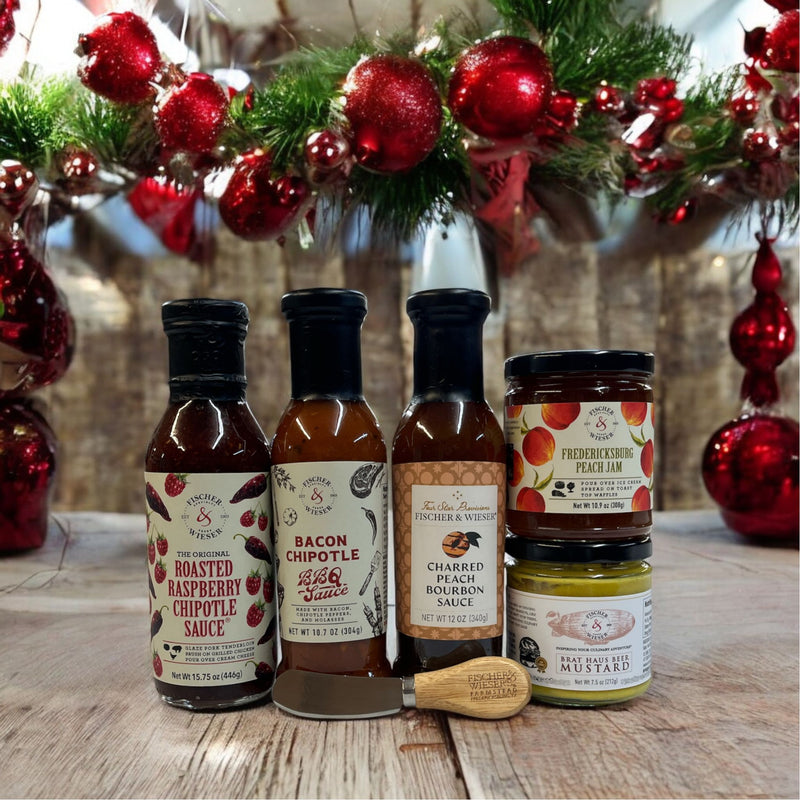 Collection of sauce bottles and a jar on a wooden surface with Christmas decorations in the background.