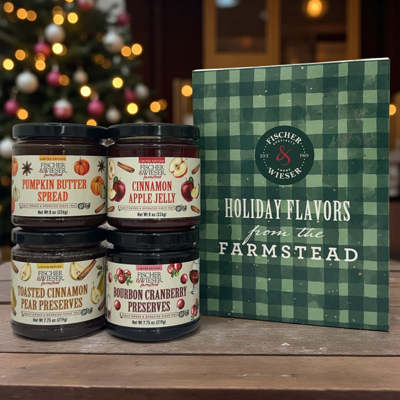 Jars of Fischer & Wiemer preserves with a holiday-themed box in front of a blurred Christmas tree.